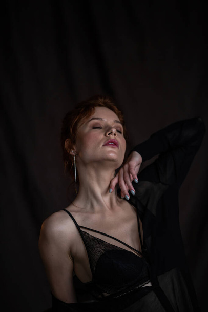 Adult beauty elegant young woman in formal evening black clothing hand on face touching. Stylish ginger curly hair sensual model bare shoulder fashionista posing at studio in fashion pantsuit and bra - Valokuva, kuva