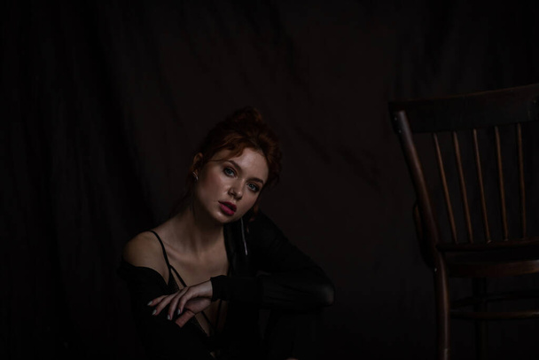 Adult beauty elegant young woman in formal evening black clothing hand on face touching. Stylish ginger curly hair sensual model bare shoulder fashionista posing at studio in fashion pantsuit and bra - Photo, Image