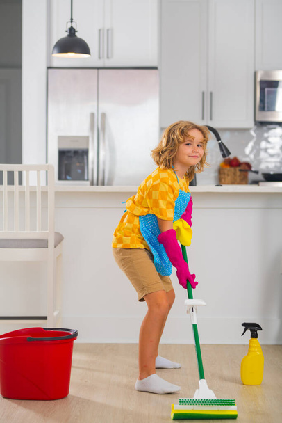 Limpieza en casa. Niño limpia en el concepto de casa. Limpieza de niños con fregona para ayudar con las tareas domésticas. Pequeño niño lindo barrer y limpiar, sobre fondo de cocina - Foto, imagen