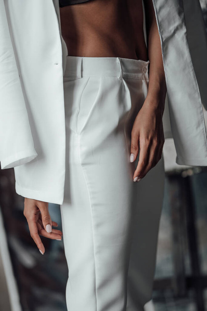 Young adult beauty swarthy woman in formal evening white suit with bra at thoughtful. Stylish black curly hair sensual african american model fashionista posing at studio in fashion pantsuit - Foto, imagen
