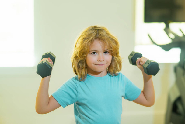 Child workout kid in gym. Kids sports exercises. Healthy kids life and sport concept. Portrait of child boy working out with dumbbells. Motivation and sport concept for children - Photo, Image