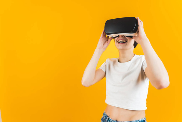 Woman smiling while using a virtual reality set. Orange background. Medium shot. High quality photo - Photo, Image