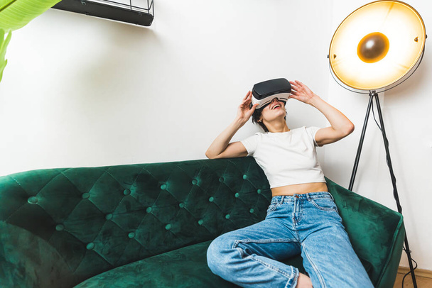  VR concept. Full medium shot. A person having great time playing with a VR headset on her couch. High quality photo - Photo, image