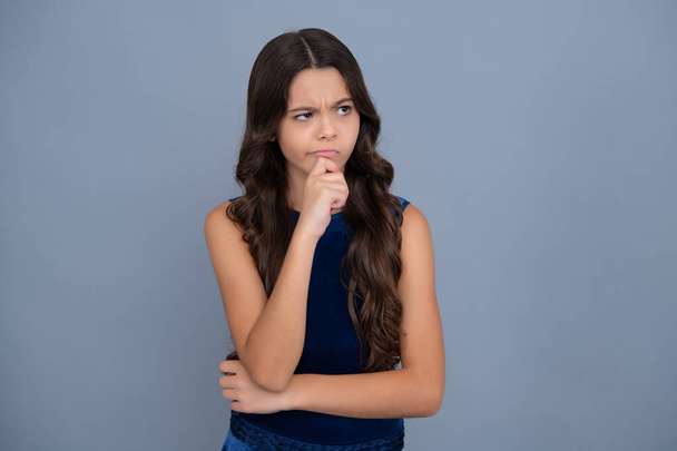 Thinking face, thoughtful emotions of teenager girl. Thoughtful teenager child thinking, pensive child making idea, posing isolated on yellow isolated background - Fotó, kép