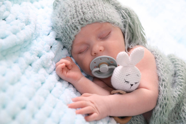 Cute newborn baby with pacifier sleeping on light blue blanket, closeup - Fotoğraf, Görsel