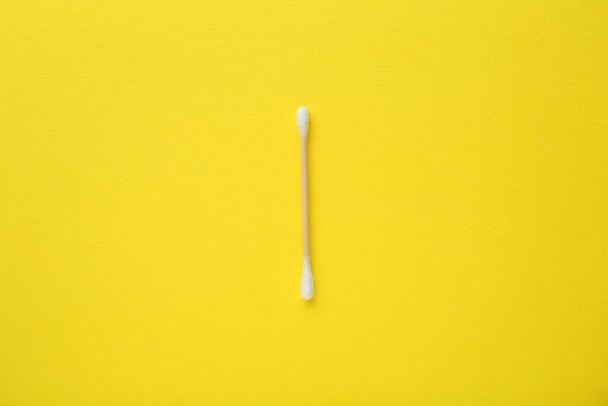 One wooden cotton bud on yellow background, top view - 写真・画像