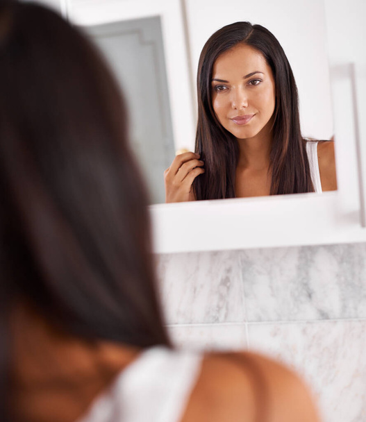 Looking good, gorgeous. a beautiful young woman looking at her face in the mirror - Valokuva, kuva