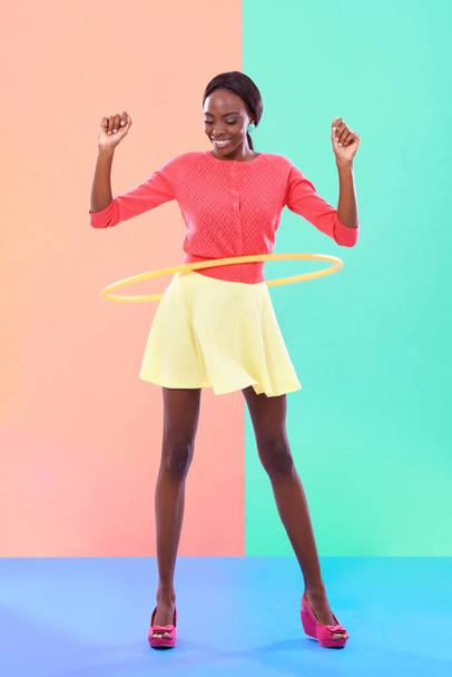 Gira ese aro hula. una atractiva joven jugando con un aro de hula sobre un fondo colorido - Foto, Imagen