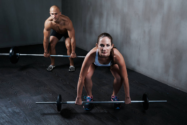 Training to become fighting fit. two people lifting barbells during a gym workout - Photo, Image