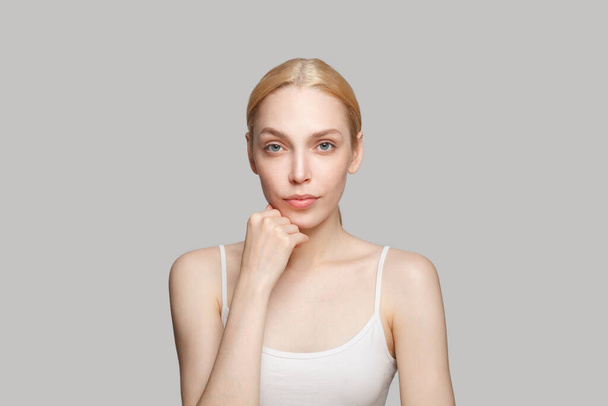 Serious beautiful woman with blonde hair isolated on grey background. Beauty, cosmetics, skincare, glamour - Photo, Image