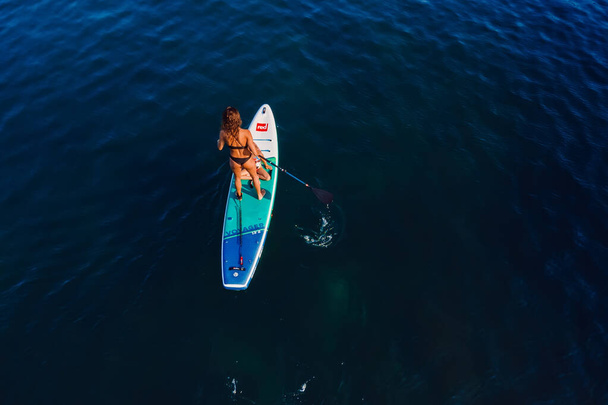 24. heinäkuuta 2022. Antalyassa, Turkissa. Hoikka nainen, jolla on lapsi soutamassa seisomaan mela aluksella hiljaisella merellä. Nainen, jolla on lapsi tytär Red Paddle SUP aluksella merellä. - Valokuva, kuva