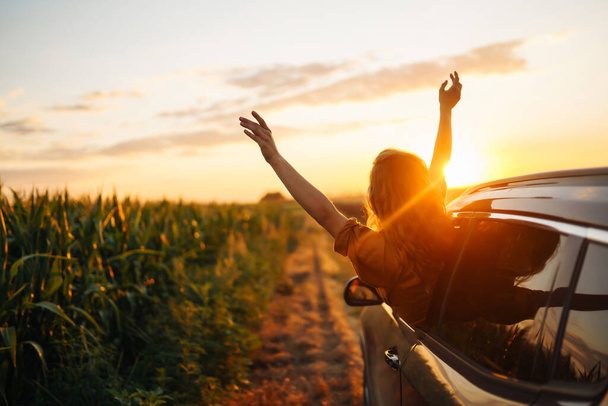 Happy woman outstretches her arms while sticking out the car window. Lifestyle, travel, tourism, nature, active life. - Foto, Bild