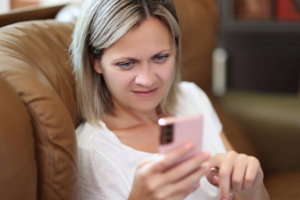 Mujer emocionada mirando la pantalla del teléfono inteligente mientras está sentado en el sofá. Concepto de aprendizaje, comunicación y compras en línea. - Foto, Imagen