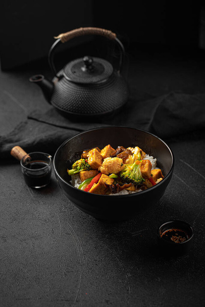 Vegetarian tofu bowl with vegetables and rice on black background - Photo, Image