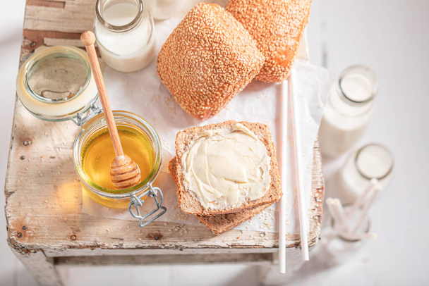 Sweet buns with honey and milk in bottle. Breakfast with milk and honey. - Photo, image