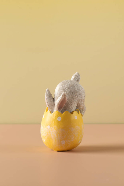 A white rabbit hid in an Easter egg on a yellow background. Festive Easter card. Happy Easter. - 写真・画像