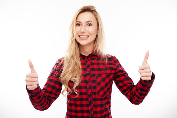 Happy blonde girl shows hand with thumbs up and smiles at the camera isolated on white background - Zdjęcie, obraz