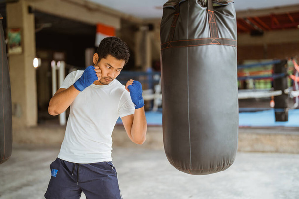 a boxer seriously punching the heavy bags at the boxing studio - Photo, image