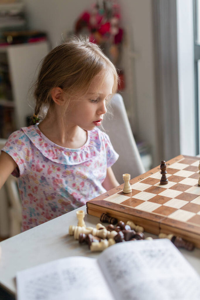 mała dziewczynka gra w szachy w pokoju - Zdjęcie, obraz