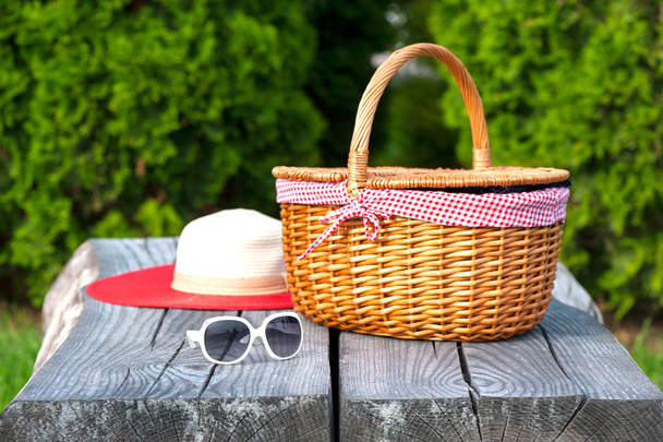 Cappello estivo con occhiali da sole bianchi e cestino in vimini sul tavolo in legno
 - Foto, immagini