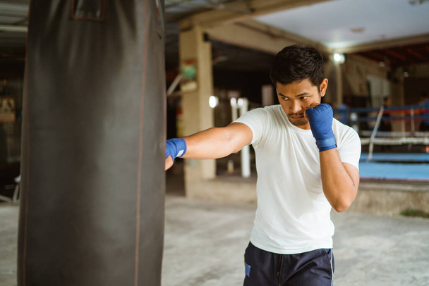 a boxer seriously punching the heavy bags at the boxing studio - 写真・画像