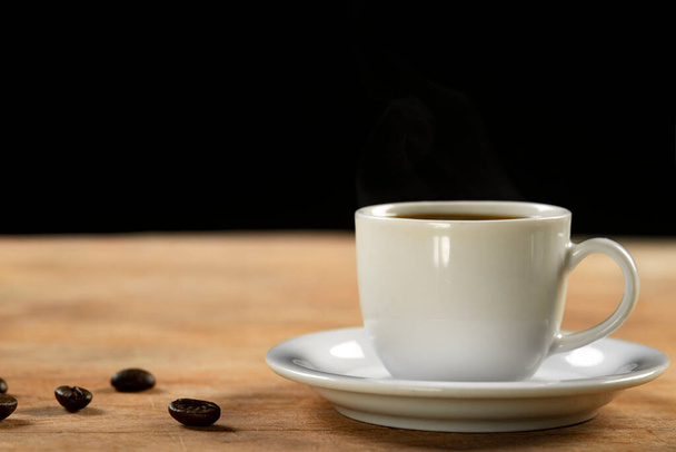 Coffee cup and coffee beans on wooden table. Black background. - Photo, Image