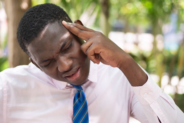 Ill African man office worker suffering from headache, health and sickness concept image for vertigo, dizziness, stress, depression, burnout, Alzheimer, brain cancer, memory loss, office syndrome - Foto, afbeelding