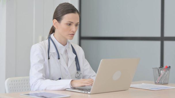 Elfoglalt fiatal orvos gépelés laptopon a klinikán - Fotó, kép