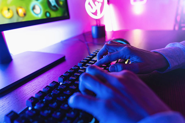 Kişisel bilgisayar koltuğu, neon rengi bulanık arkaplan akışı için klavyesi olan profesyonel sanal video oyunu stüdyosu.. - Fotoğraf, Görsel