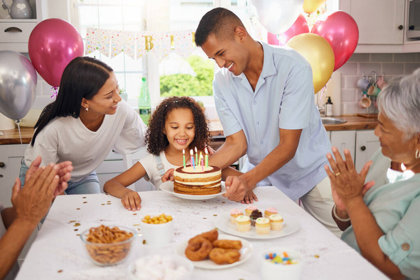 Dziecko, tort urodzinowy i uroczyste przyjęcie z rodziną i rodzicami szczęśliwej i podekscytowanej dziewczyny gotowej zdmuchnąć świeczki w domu. Słodki dzieciak przy stole w domu Puerto Rico z balonami i przekąskami. - Zdjęcie, obraz