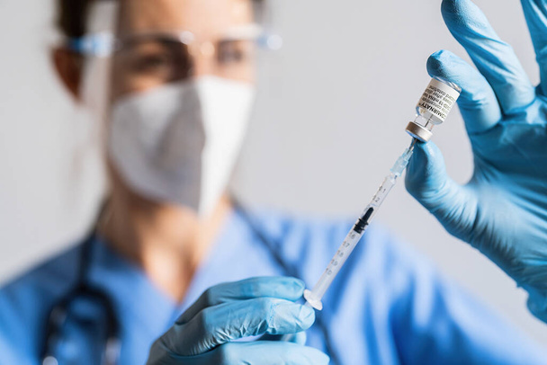 BERLIN, ΓΕΡΜΑΝΙΑ 10 ΔΕΚΕΜΒΡΙΟΥ 2021: Ένας νοσηλευτής αντλεί δόση από ένα φιαλίδιο εμβολίου Pfizer-BioNTech που έχει τοποθετηθεί στο κέντρο εμβολιασμού. - Φωτογραφία, εικόνα