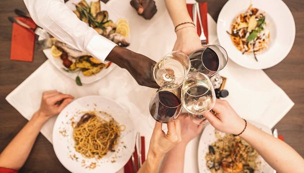 Groep gelukkige vrienden die pasta, pizza en wijn eten en drinken - Foto, afbeelding