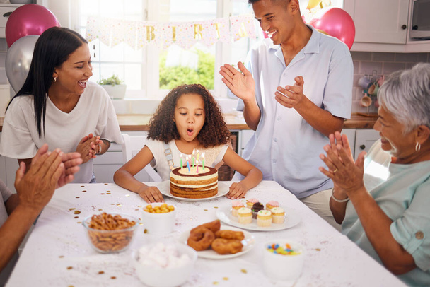 День народження, діти і торт з дівчиною на святкуванні з сім'єю на вечірці, вириваючи свої свічки, щоб зробити бажання. Діти, оплески і щасливі з дочкою, батьки і бабусі і дідусі вдома
. - Фото, зображення