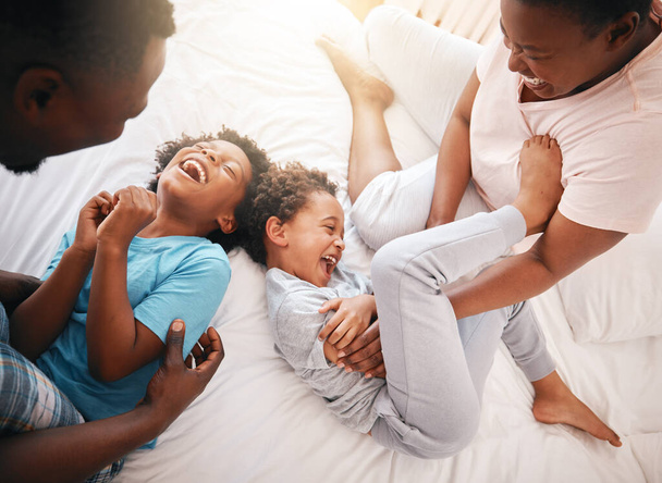 Tickle, funny and relax with black family in bedroom for bonding, playful and affectionate. Laugh, happiness and crazy with parents playing with children at home for wake up, morning and silly. - Fotografie, Obrázek