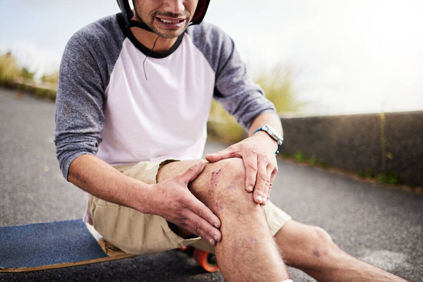 Τραυματισμός, πόνος στον άνδρα και το γόνατο μετά από ατύχημα με σκέιτμπορντ, εξάσκηση και εκμάθηση πατινάζ. Ενεργός, κακός και skateboarder με μια μελανιά, σπασμένα κόκαλα ή κρατώντας ένα επίπονο πόδι στο δρόμο, ενώ πατινάζ. - Φωτογραφία, εικόνα