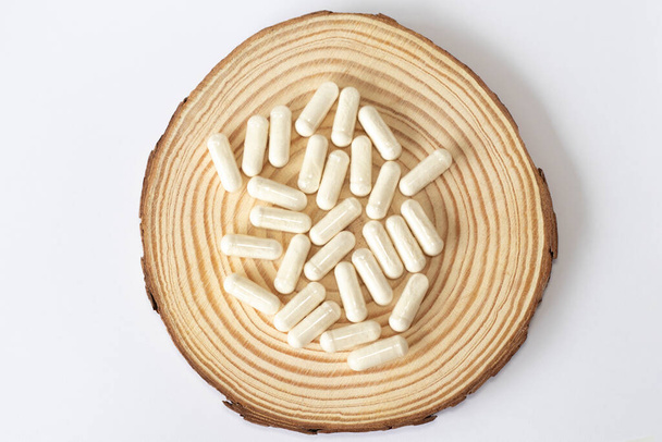 Compléments enzymatiques blancs sur fond rond en bois. - Photo, image