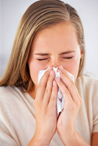 Shes getting the sniffles. a young woman blowing her nose into a tissue - Foto, afbeelding