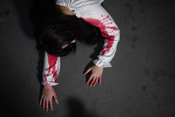 Straszna kobieta w białej sukience z plamą krwi po morderstwie jak duch w korytarzu nawiedzonego domu błąka się w ciemności, Halloween kostium party, scena horroru, koszmar - Zdjęcie, obraz