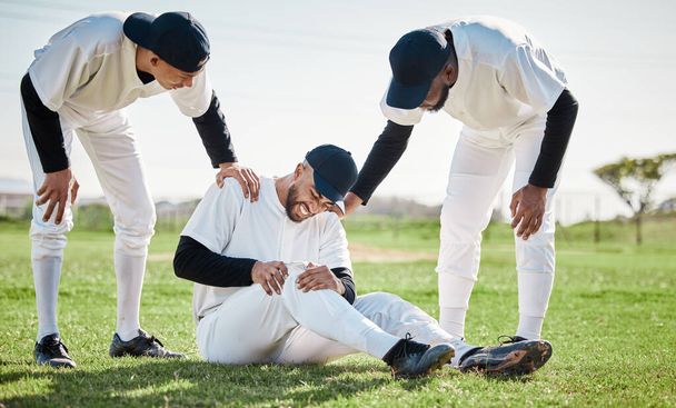 Baseball, týmová pomoc a muž se zraněním na hřišti po nehodě, pád nebo cvičení v zápase. Sportovní, tréninkový a mužský hráč s fibromyalgií, zánětlivou bolestí nebo zlomeným kolenem - Fotografie, Obrázek