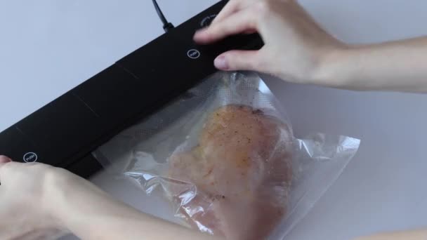 Il processo di aspirare un pezzo di petto di pollo marinato in spezie in un sacchetto in una macchina imballatrice - Filmati, video