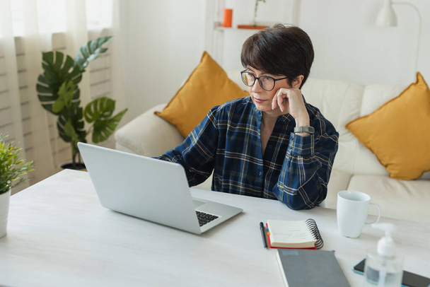 Бізнес-леді, яка працює на ноутбуці, сидячи вдома в піжамі, носить і управляє своїм бізнесом через домашній офіс під час концепції Coronavirus або Covid-19. - Фото, зображення