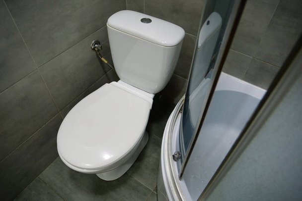 WC-huoneen sisustus valkoinen wc-kulho, suihkukaappi ja harmaat seinälaatat - Valokuva, kuva