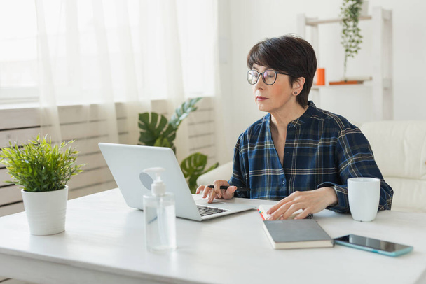 Bizneswoman pracuje na laptopie siedząc w domu w domu w piżamie nosi i zarządza swoją firmą za pośrednictwem biura domowego podczas Coronavirus lub koncepcja Covid-19 - Zdjęcie, obraz