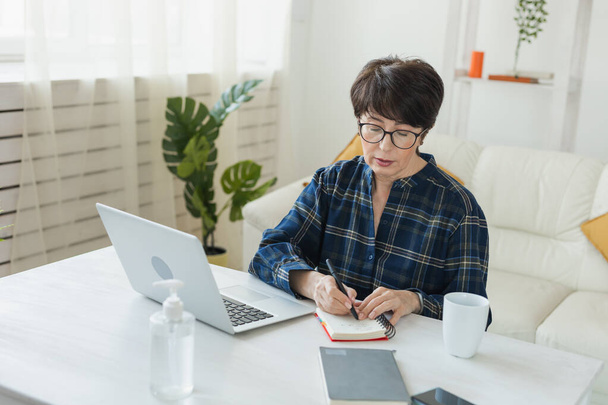 Imprenditrice che lavora sul computer portatile seduta a casa in pigiama indossa e gestisce la sua attività tramite home office durante il concetto Coronavirus o Covid-19 - Foto, immagini