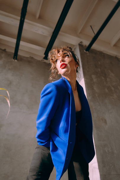 A beautiful glamorous girl with a slim figure in sunglasses in a blue jacket and green at a trendy hot stylish fashion photo shoot posing in a photo studio. - 写真・画像