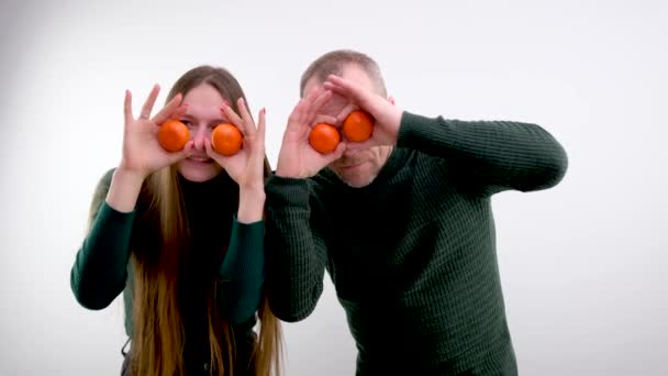 man and girl fooling around balding man and long-haired daughter joking playing troll each other tangerines holding tangerines near eyes for sale fresh fruits in city buy exotic fruits at low prices - Metraje, vídeo