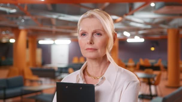 Concentrated professional lady with pretty face posing for close up portrait indoors. Confident smiling mature adult European stylish classy woman standing at office, attentively listening colleague - Footage, Video