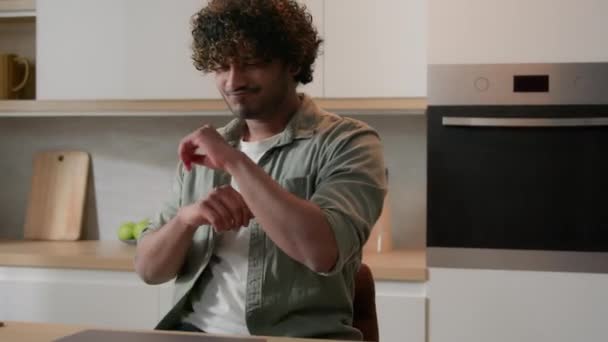 Indiase gelukkig actieve man Spaanse freelancer student jongen Arabische zakenman Indiase man dansen grappig bewegende dans zitten aan keukentafel met gesloten laptop vieren dag vrij werk thuis - Video