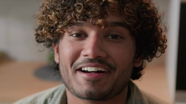 Közelkép mosolygós arab férfi lakástulajdonos göndör haj vlogger nézd meg a kamerát a konyhában. Portré indiai férfi arc mosollyal beltérben. Fejlövés etnikai srác üzleti videó konferencia hívás webkamera nézet - Felvétel, videó