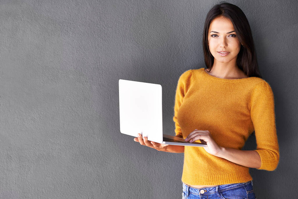 Я люблю свій легкий ноутбук. Портрет привабливої молодої жінки, що тримає ноутбук, стоячи на сірій стіні
 - Фото, зображення